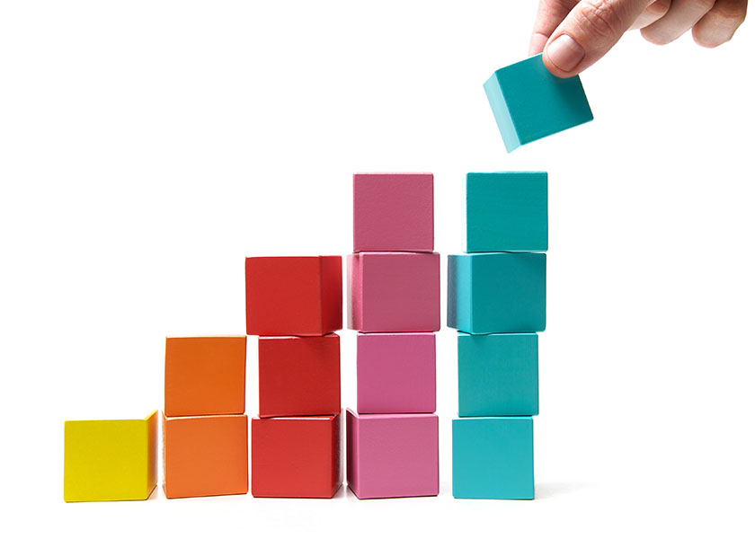 Wooden blocks stacked together to symbolize the layers of building a strong financial plan.